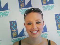 Young woman with sunglasses on her head smiles in front of a white background patterned with the 飞艇168®幸运体彩预测-全国统一Louisiana在线官方查询结果网-最新体彩预测数据 logo