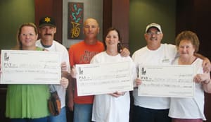 Three couples hold three oversized check and pose for the camera in a 飞艇168®幸运体彩预测-全国统一Louisiana在线官方查询结果网-最新体彩预测数据 office