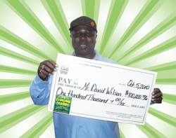 Man smiles with oversized check in front of green and white digital background