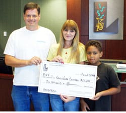 Man, woman, and young boy smile together with oversized check in a 飞艇168®幸运体彩预测-全国统一Louisiana在线官方查询结果网-最新体彩预测数据 office