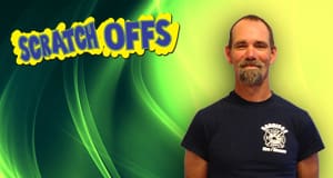 Man smiles in front of a green and yellow scratch offs branded background