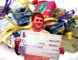 Man smiles with an oversized check in front of an image of wrapped gifts
