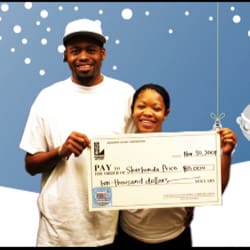 Man and woman smile with oversized check in front of a digital blue and white snowy background