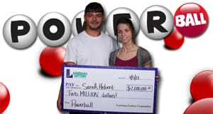 Man and woman hold oversized check in front of a white Powerball branded background