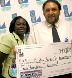 Man and woman smile with oversized check in front of a white background patterned with the 飞艇168®幸运体彩预测-全国统一Louisiana在线官方查询结果网-最新体彩预测数据 logo
