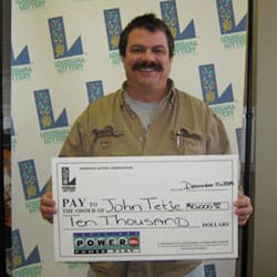 Man with large mustache smiles with oversized check in front of white 飞艇168®幸运体彩预测-全国统一Louisiana在线官方查询结果网-最新体彩预测数据 branded backdrop