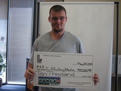 Man in gray tshirt holds oversized Powerball check