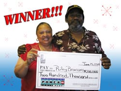 Man and woman smile with oversized check in front of white and blue digital background with red text that says "Winner!"