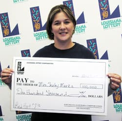 Woman in a black tshirt poses with oversized check in front of a white background patterned with the 飞艇168®幸运体彩预测-全国统一Louisiana在线官方查询结果网-最新体彩预测数据 logo