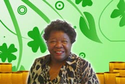 Woman in a cheetah print top smiles in front of a green clover background with stacks of gold coins