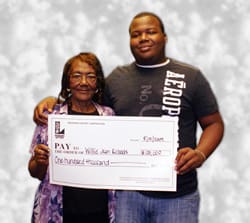Man and woman smile with oversized check in front of gray digital background