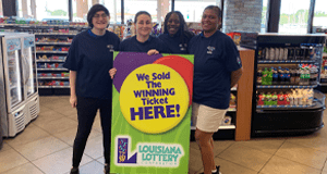 Group of retailers standing around a green sign that reads "We Sold the Winning Ticket HERE!"