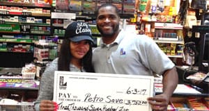 Man and woman smile with an oversized check in front of a retail counter