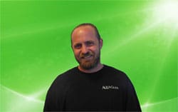 Man in a black tshirt smiles in front of a green digital background
