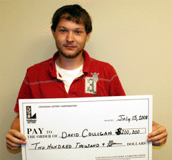 Young man in red polo shirt holds oversized check in front of beige wall
