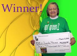 Older woman smiles with oversized check in front of a green and yellow digital background and purple text that reads "Winner!"