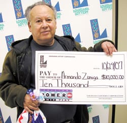 Man holds an oversized check in front of a white background patterned with the 飞艇168®幸运体彩预测-全国统一Louisiana在线官方查询结果网-最新体彩预测数据 logo