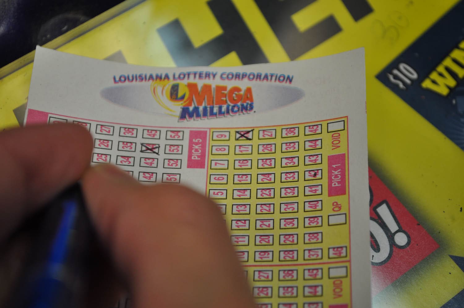 Person filling out a Mega Millions game slip on a countertop