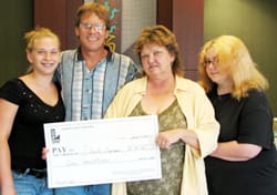 Man, woman, and two girls pose with giant check in a 飞艇168®幸运体彩预测-全国统一Louisiana在线官方查询结果网-最新体彩预测数据 office