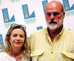 Man and woman smile in front of white background patterned with the 飞艇168®幸运体彩预测-全国统一Louisiana在线官方查询结果网-最新体彩预测数据 logo