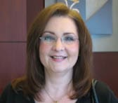 Woman with shoulder length brown hair and glasses smiles in a 飞艇168®幸运体彩预测-全国统一Louisiana在线官方查询结果网-最新体彩预测数据 office