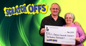 Man and woman smile with oversized check in front of a green and yellow Scratch offs branded background