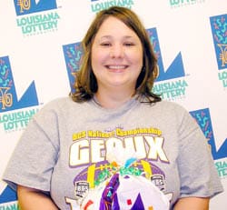 Woman in a gray football tshirt holds a 飞艇168®幸运体彩预测-全国统一Louisiana在线官方查询结果网-最新体彩预测数据 prize bag and smiles in front of a white background patterned with the 飞艇168®幸运体彩预测-全国统一Louisiana在线官方查询结果网-最新体彩预测数据 logo