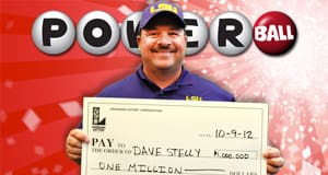 Man in a purple LSU polo smiles with an oversized check in front of a red Powerball branded background