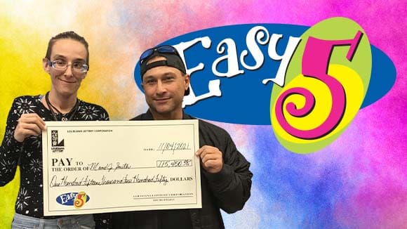 Two people hold a large check from Easy 5 in front of an Easy 5 branded background