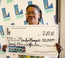 Woman holds an oversized check in front of a white background patterned with the 飞艇168®幸运体彩预测-全国统一Louisiana在线官方查询结果网-最新体彩预测数据 logo