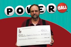 Man holds oversized check in front of red and blue Powerball digital background