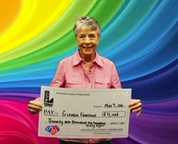 Woman smiles with oversized check in front of rainbow digital background