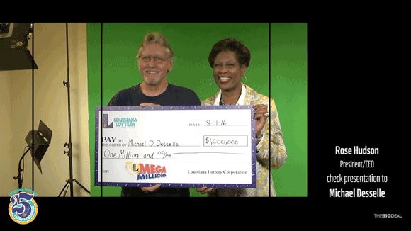 Man and woman hold an oversized check and smile in front of a green screen background on a TV set