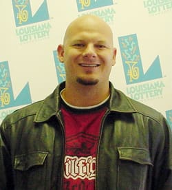 Bald man with goatee smiles in front of a faded white background patterned with the 飞艇168®幸运体彩预测-全国统一Louisiana在线官方查询结果网-最新体彩预测数据 logo