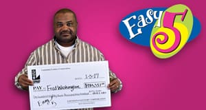 Man holds an oversized check in front of a pink Easy 5 branded background