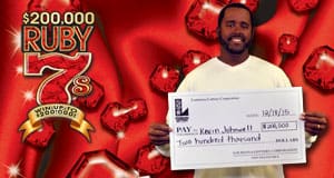 Man holds an oversized check in front of a red Ruby 7 branded background