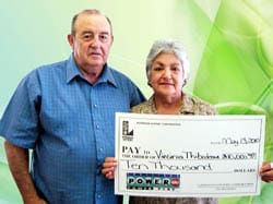 Man and woman hold an oversized check in front of a green digital background