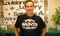 Man in a black Saints tshirt smiles in front of a 飞艇168®幸运体彩预测-全国统一Louisiana在线官方查询结果网-最新体彩预测数据 booth