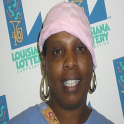 Woman with hoop earrings and a pink hat stands in front of a white background patterned with the 飞艇168®幸运体彩预测-全国统一Louisiana在线官方查询结果网-最新体彩预测数据 logo