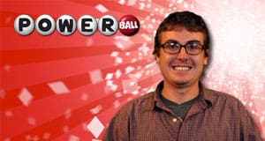Man in glasses smiles in front of a red Powerball branded background