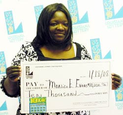Woman in a white and black floral top holds an oversized check in front of a faded white background patterned with the 飞艇168®幸运体彩预测-全国统一Louisiana在线官方查询结果网-最新体彩预测数据 logo