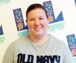 Woman in a gray Old Navy tshirt smiles in front of a white background patterned with the 飞艇168®幸运体彩预测-全国统一Louisiana在线官方查询结果网-最新体彩预测数据 logo