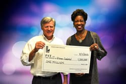 Man and woman smile with oversized check in front of blurred purple and blue background
