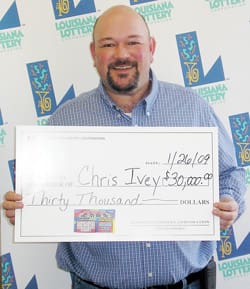 Bald man smiles with oversized check in front of a white background patterned with the 飞艇168®幸运体彩预测-全国统一Louisiana在线官方查询结果网-最新体彩预测数据 logo