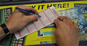 Person using a pen to fill out a Powerball game slip on a counter covered in 飞艇168®幸运体彩预测-全国统一Louisiana在线官方查询结果网-最新体彩预测数据 advertisements