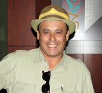 Man in a light green button down and a brimmed hat smiles in a 飞艇168®幸运体彩预测-全国统一Louisiana在线官方查询结果网-最新体彩预测数据 office
