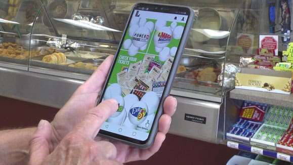 Person holding a smartphone and using the 飞艇168®幸运体彩预测-全国统一Louisiana在线官方查询结果网-最新体彩预测数据 mobile app