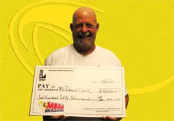 Mustached man smiles with oversized check in front of a yellow branded background