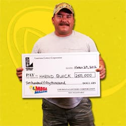 Man with mustache and hat smiles with oversized check in front of a yellow branded background