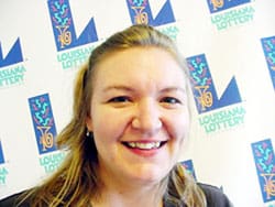 Woman with blonde hair smiles in front of a white background patterned with the 飞艇168®幸运体彩预测-全国统一Louisiana在线官方查询结果网-最新体彩预测数据 logo